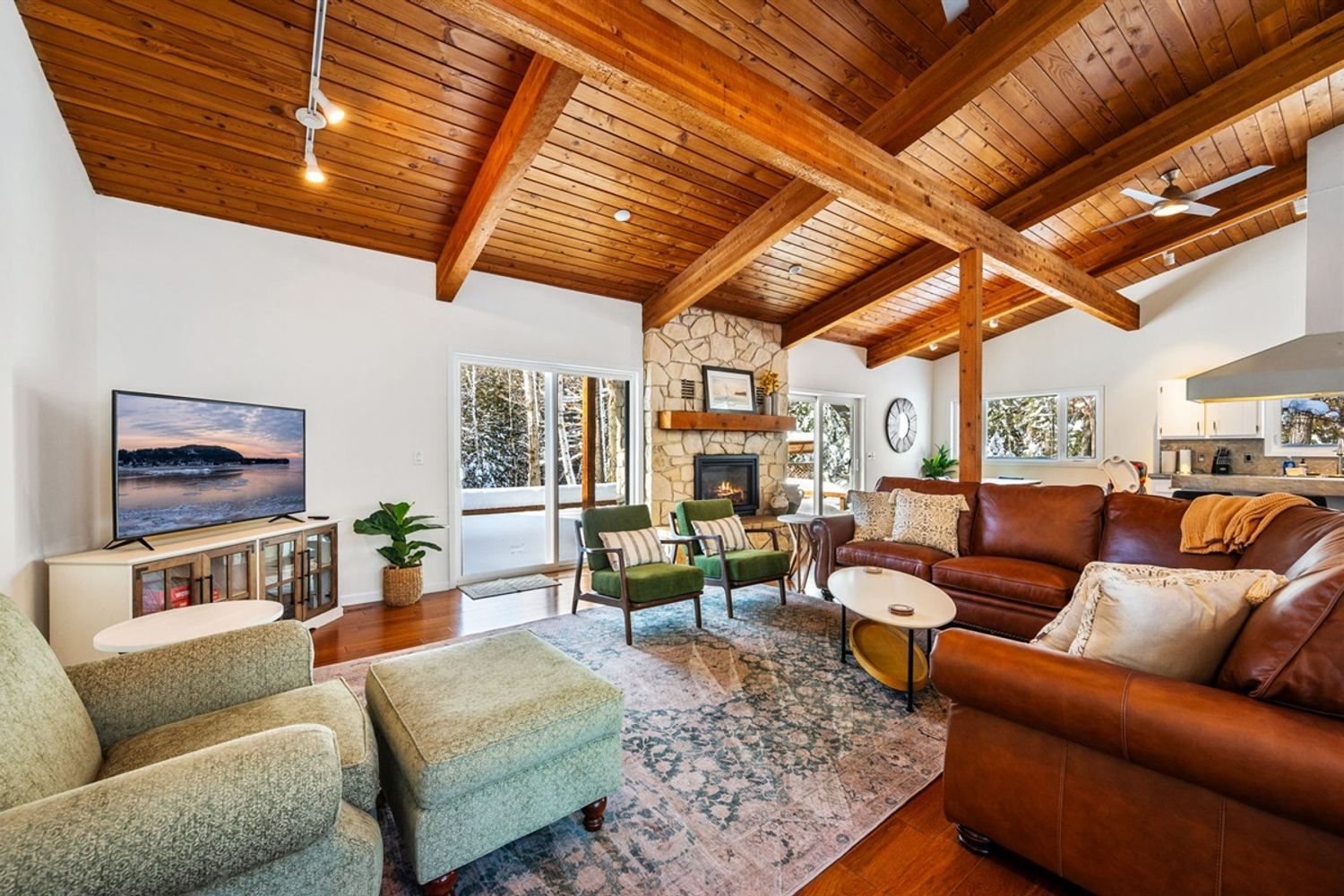 The vaulted, wood-beamed living room of a Moonsail home in Door County, with a stone fireplace